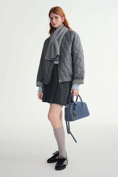 Model wearing a gray quilted jacket with a skirt and handbag
