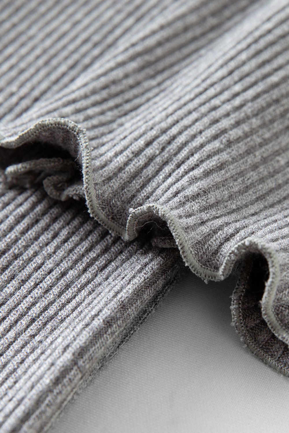 Close-up of pleated hem detail on gray ribbed dress