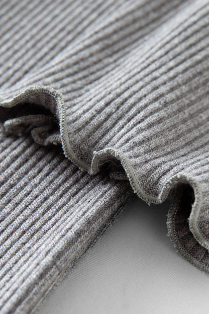 Close-up of pleated hem detail on gray ribbed dress