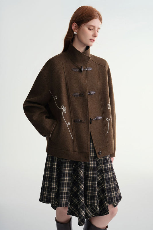 Model wearing a brown toggle jacket with a plaid skirt