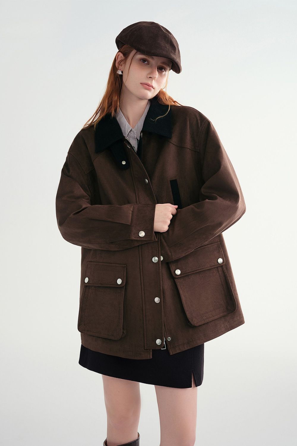 Model wearing a brown button-up jacket with front flap pockets and a mini skirt