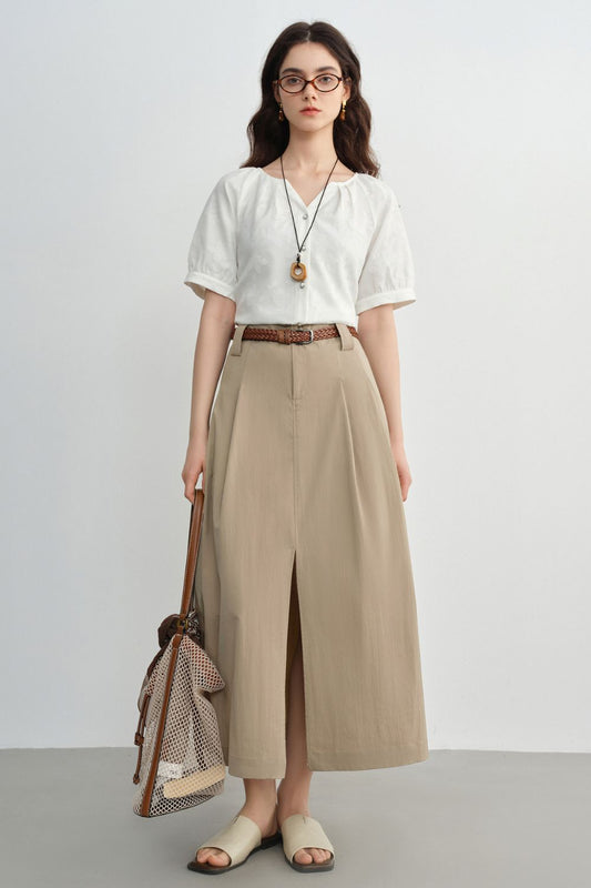 Model wearing a beige A-line midi skirt with a front slit, styled with a white blouse