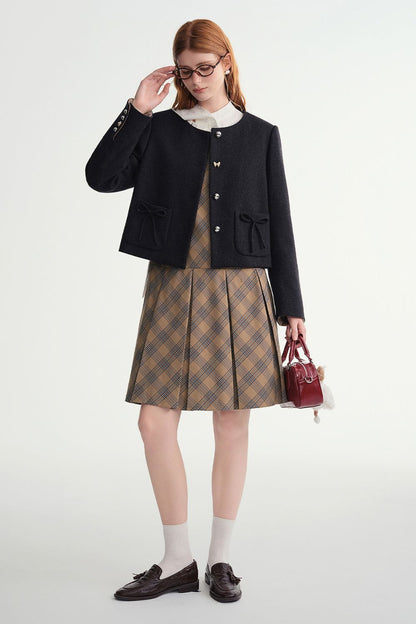 Model styling black cropped jacket with a plaid skirt and handbag