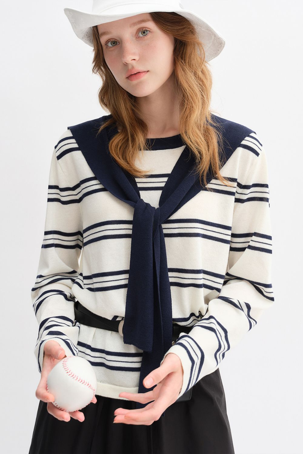 Mid-length view of model in striped top with navy collar and black skirt