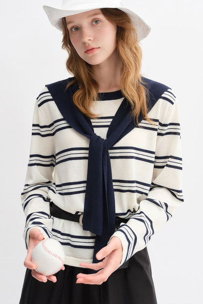 Mid-length view of model in striped top with navy collar and black skirt