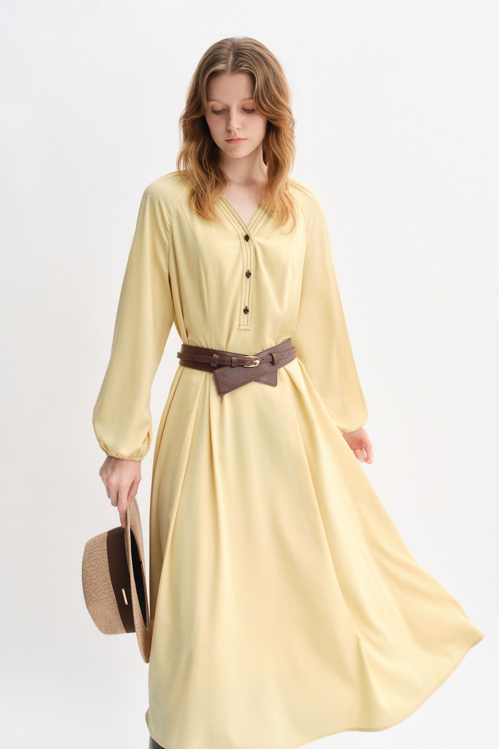 Front view of yellow flowy belted dress styled with long boots