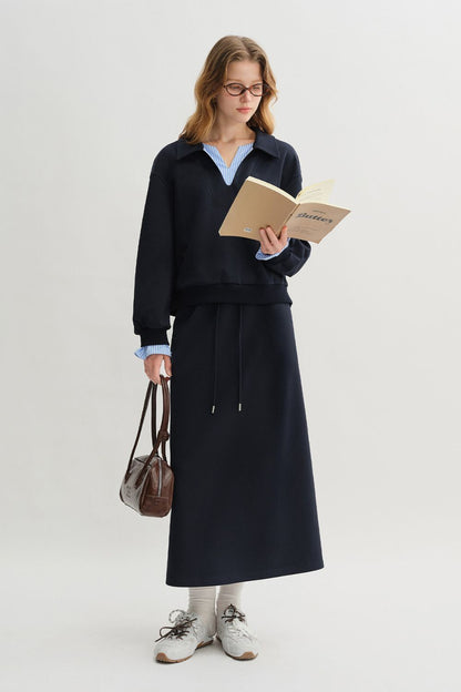 Side view of woman in navy blue pullover with light blue striped collar and cuffs, styled with matching skirt