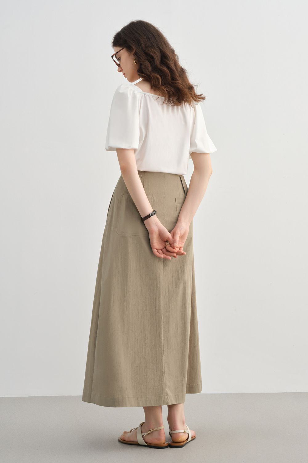 Back view of beige midi skirt styled with a white blouse