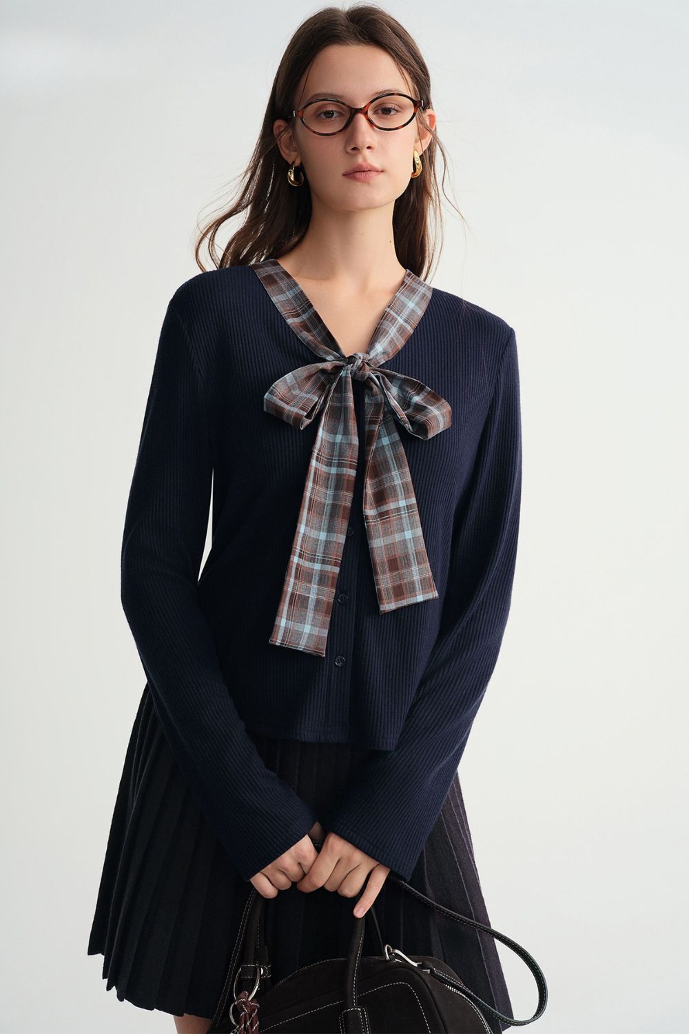 Front view of navy blue pleated skirt outfit with plaid bow detail