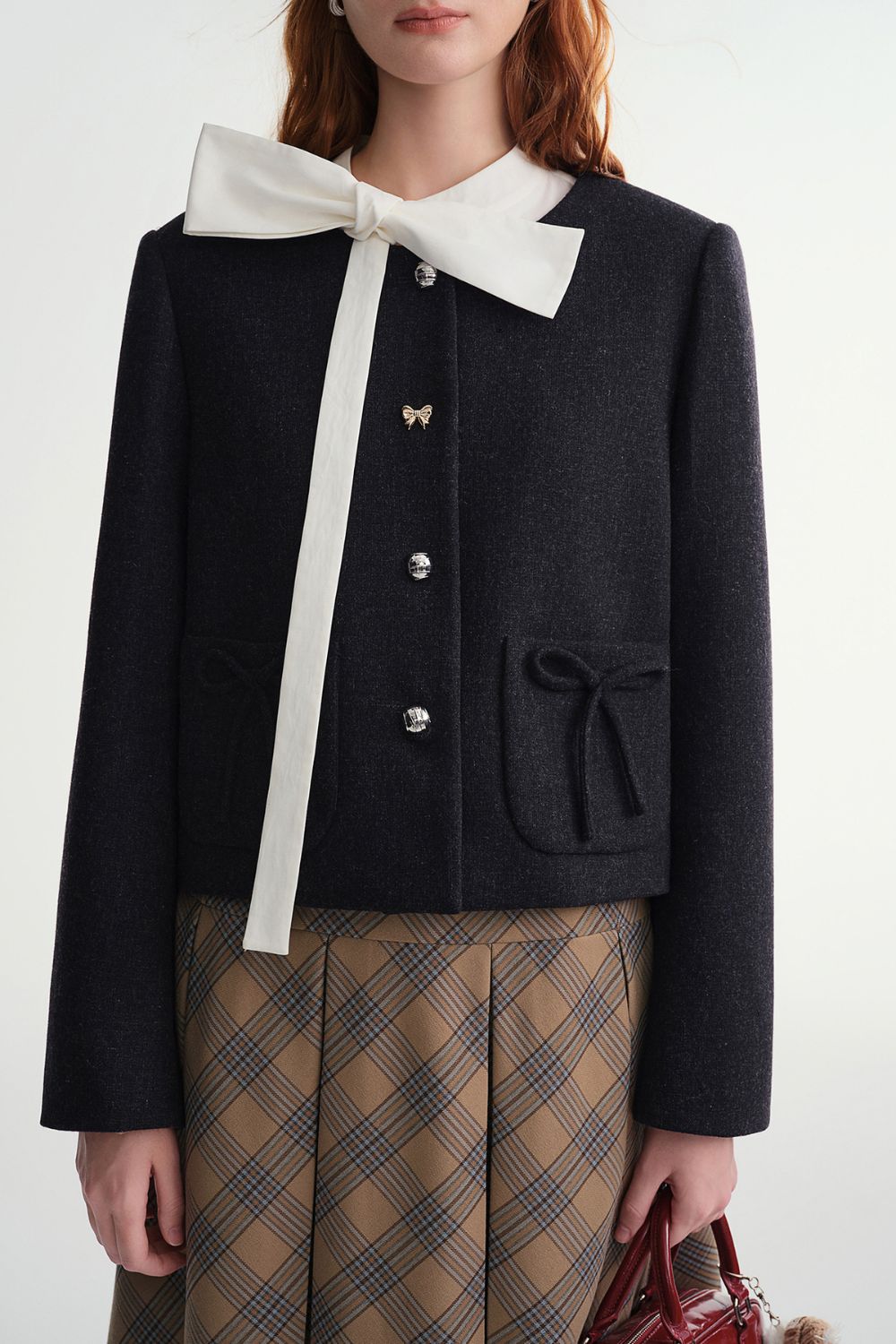 Close-up front view of black cropped jacket with button closure and pocket details