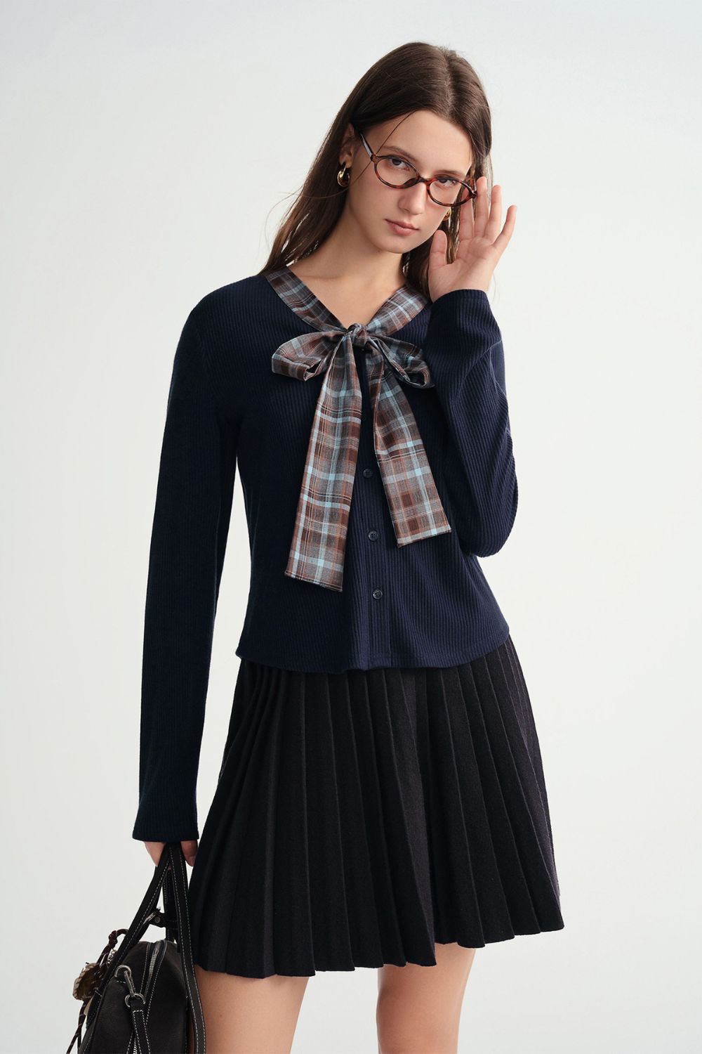 Side view of navy blue pleated skirt and plaid bow top
