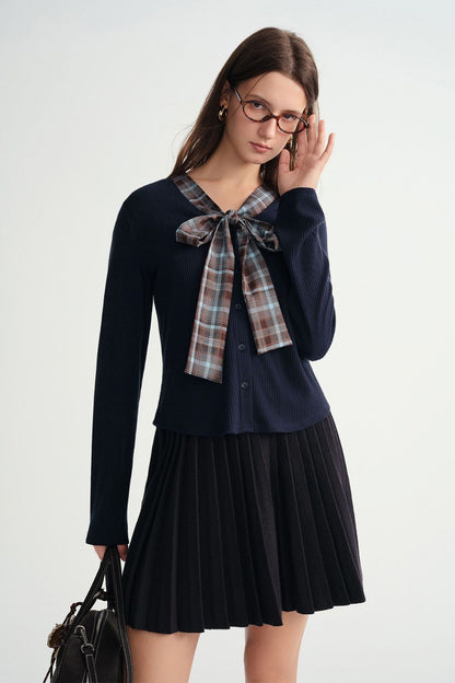 Side view of navy blue pleated skirt and plaid bow top