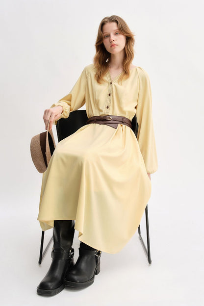 Model seated while wearing yellow long-sleeve belted dress