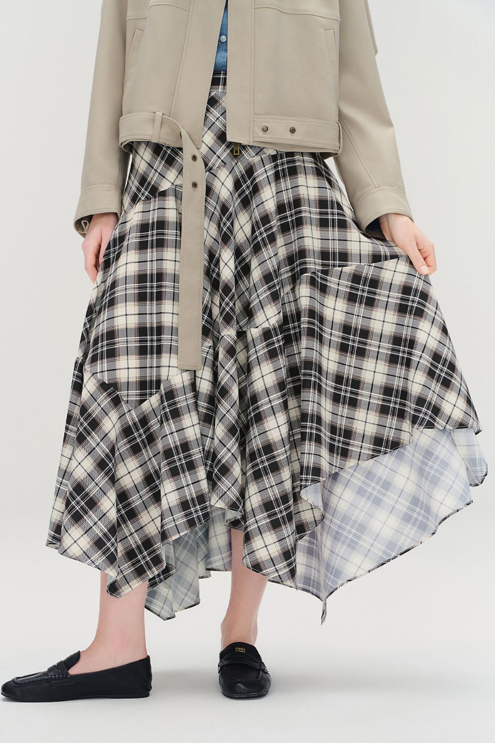Front view of plaid high-low skirt styled with a beige jacket