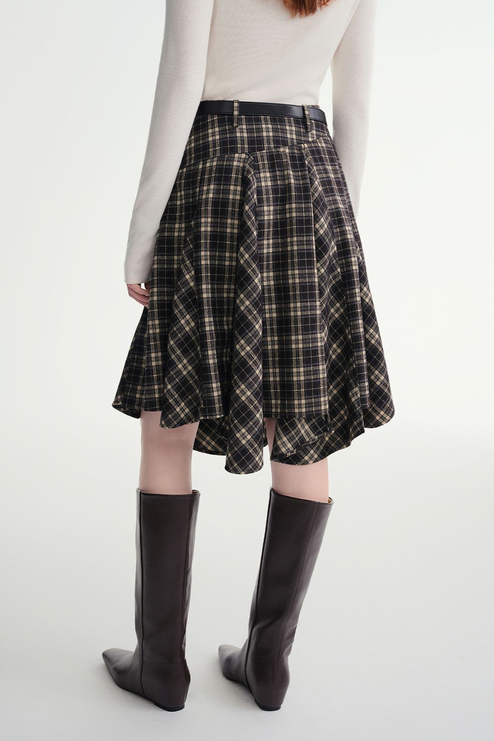 Back view of plaid skirt showing flared hemline with knee-high boots