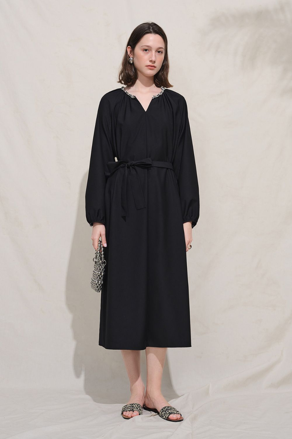 Model in black dress standing against neutral background