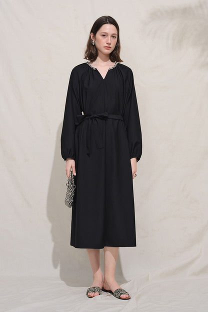 Model in black dress standing against neutral background