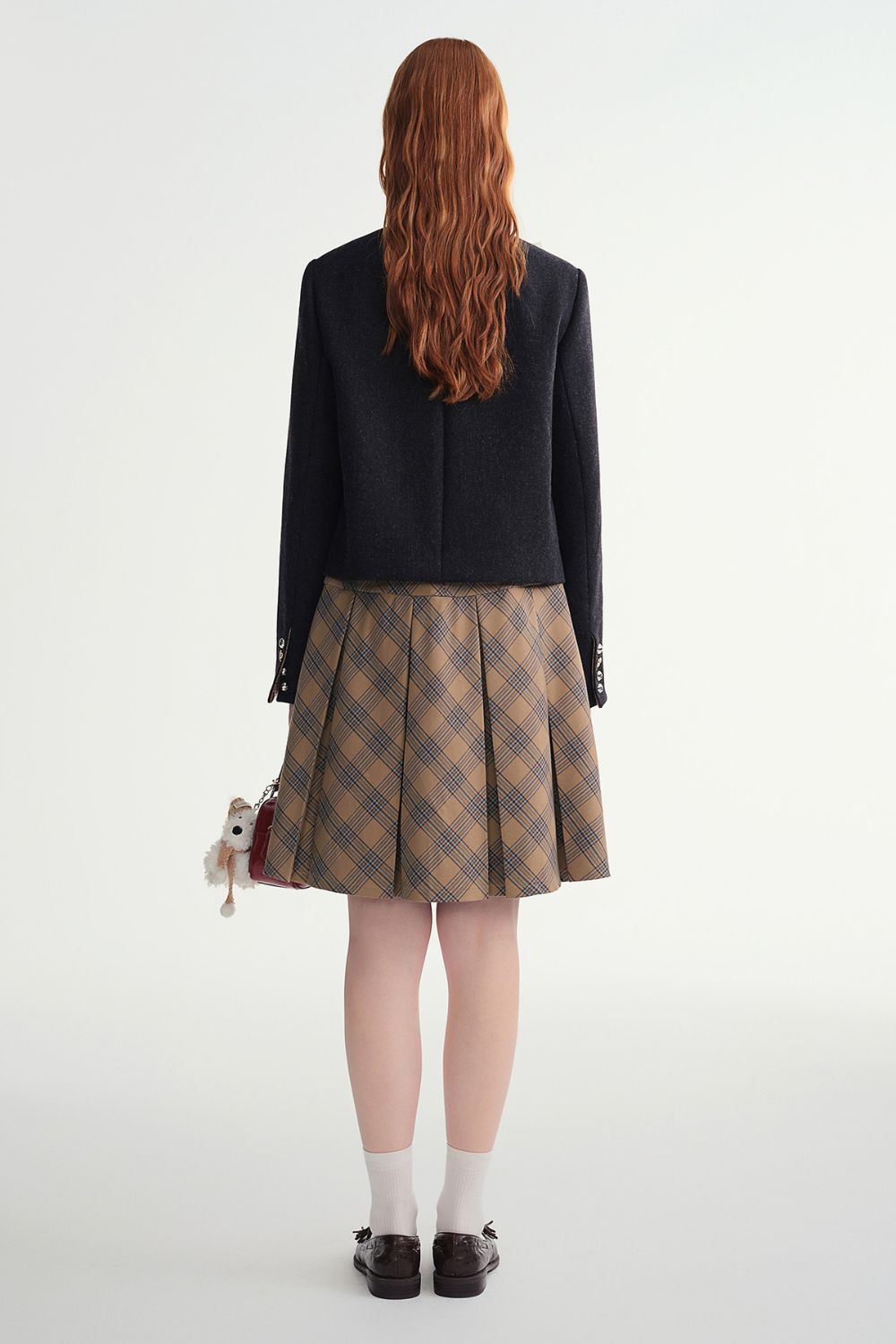 Back view of black cropped jacket paired with a plaid skirt