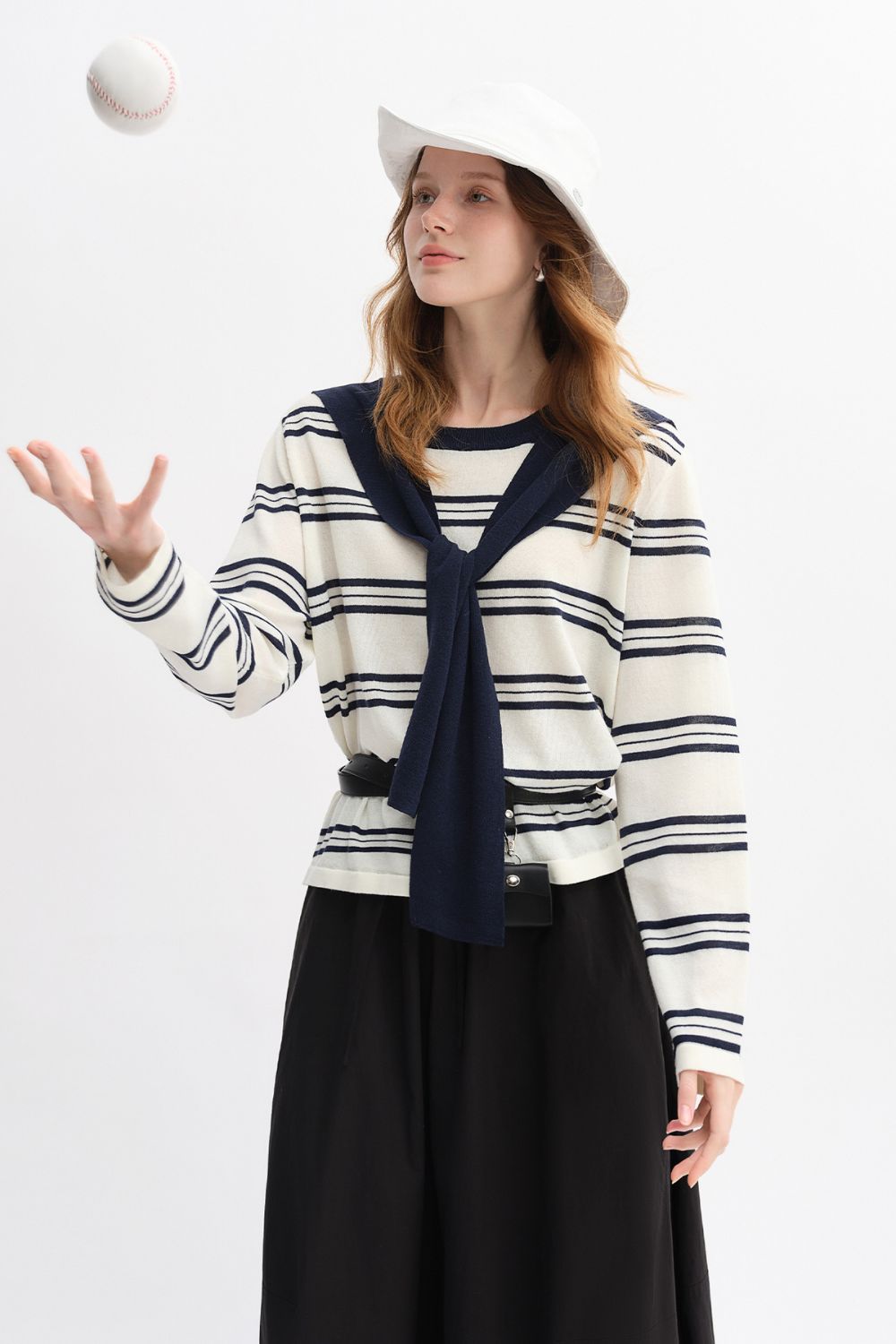 Model tossing a ball while wearing striped top with navy collar and black skirt