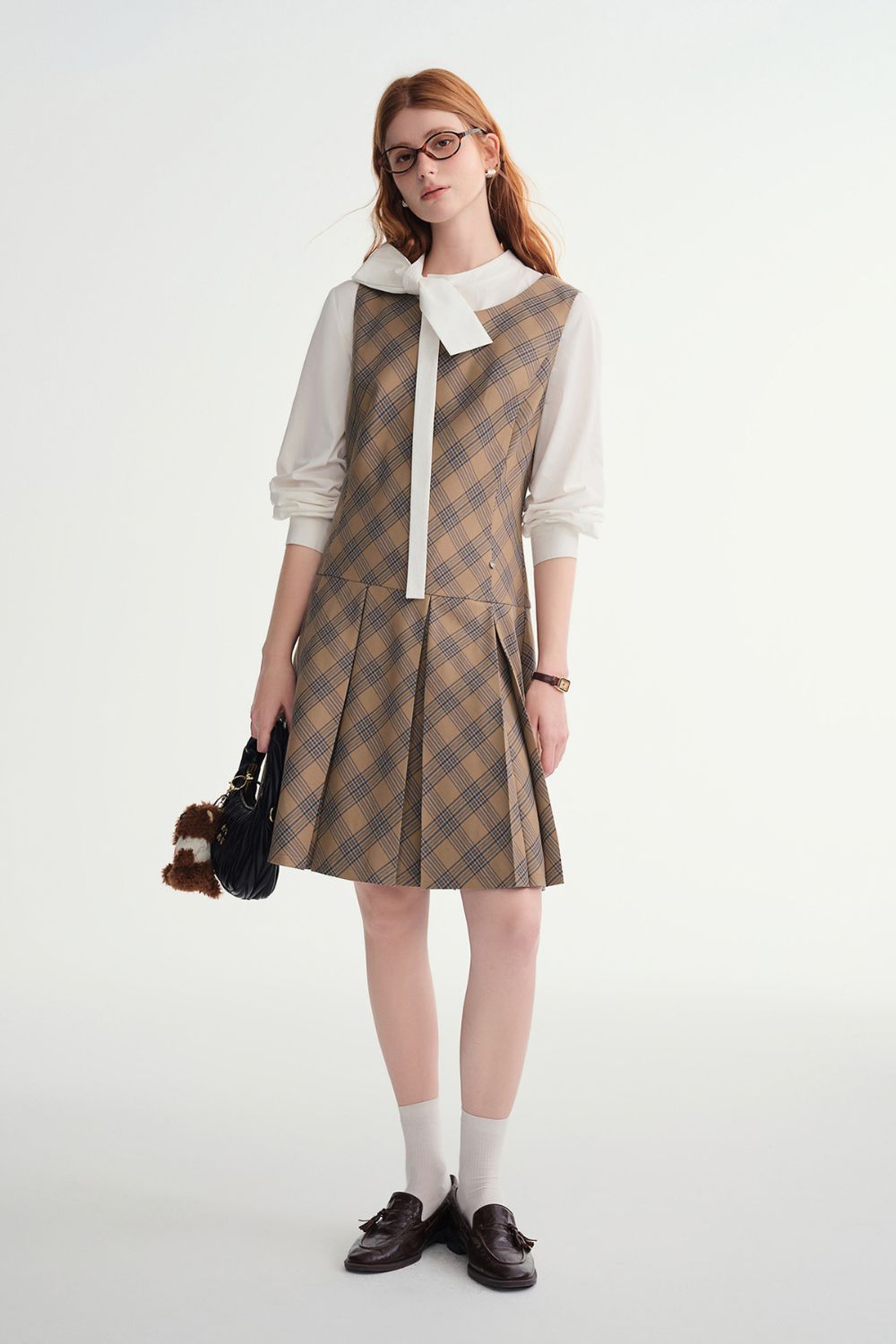 Side view of plaid sleeveless dress layered over white blouse