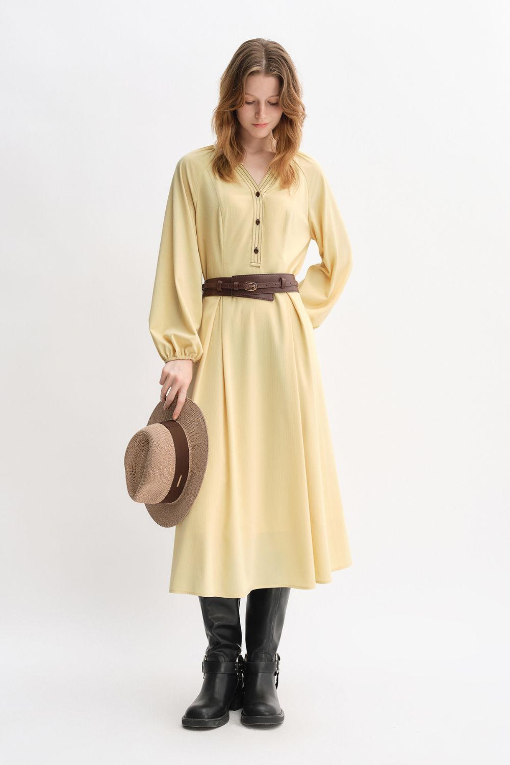 Angled standing view of yellow belted dress with hat accessory