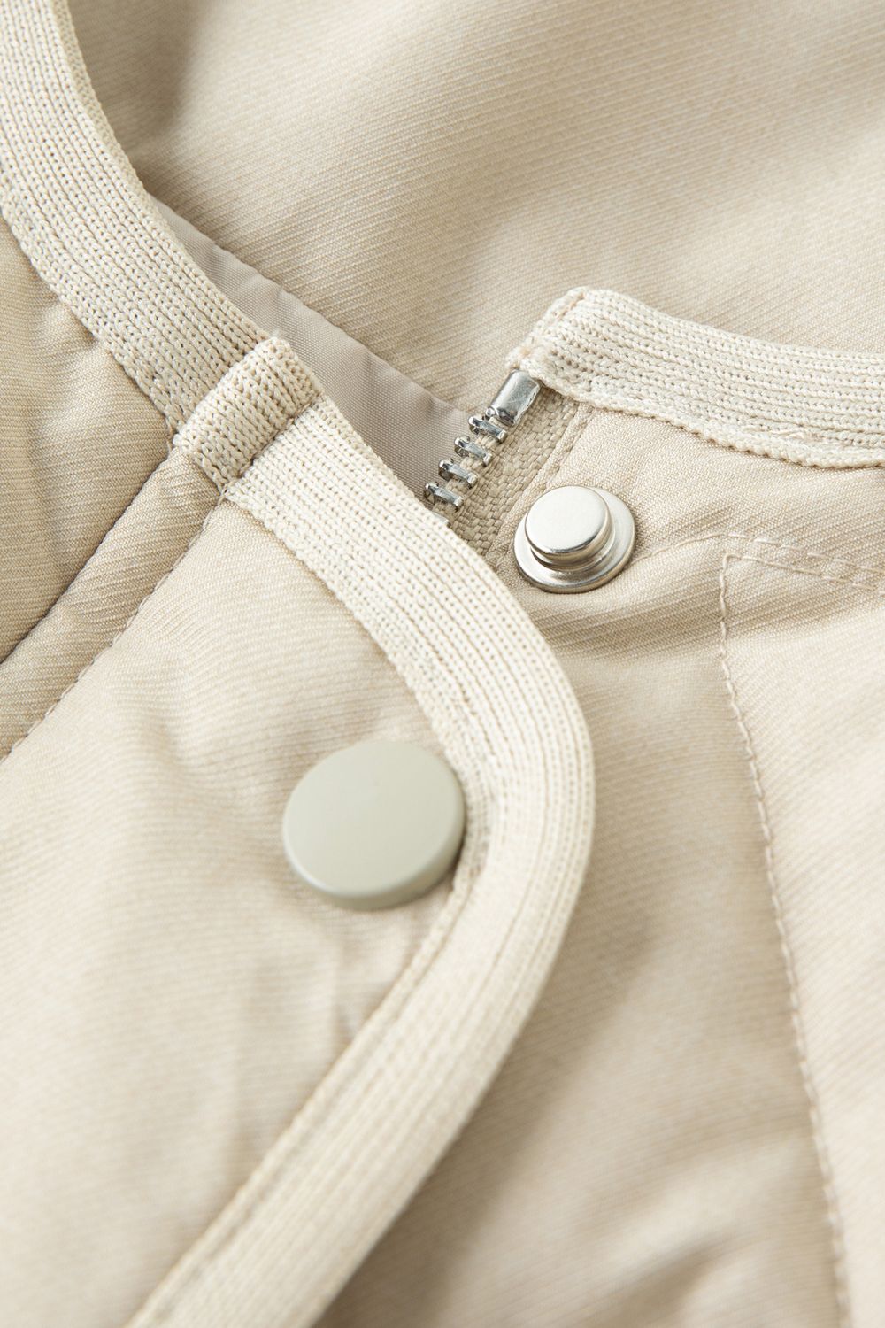 Close-up of beige jacket snap button closure