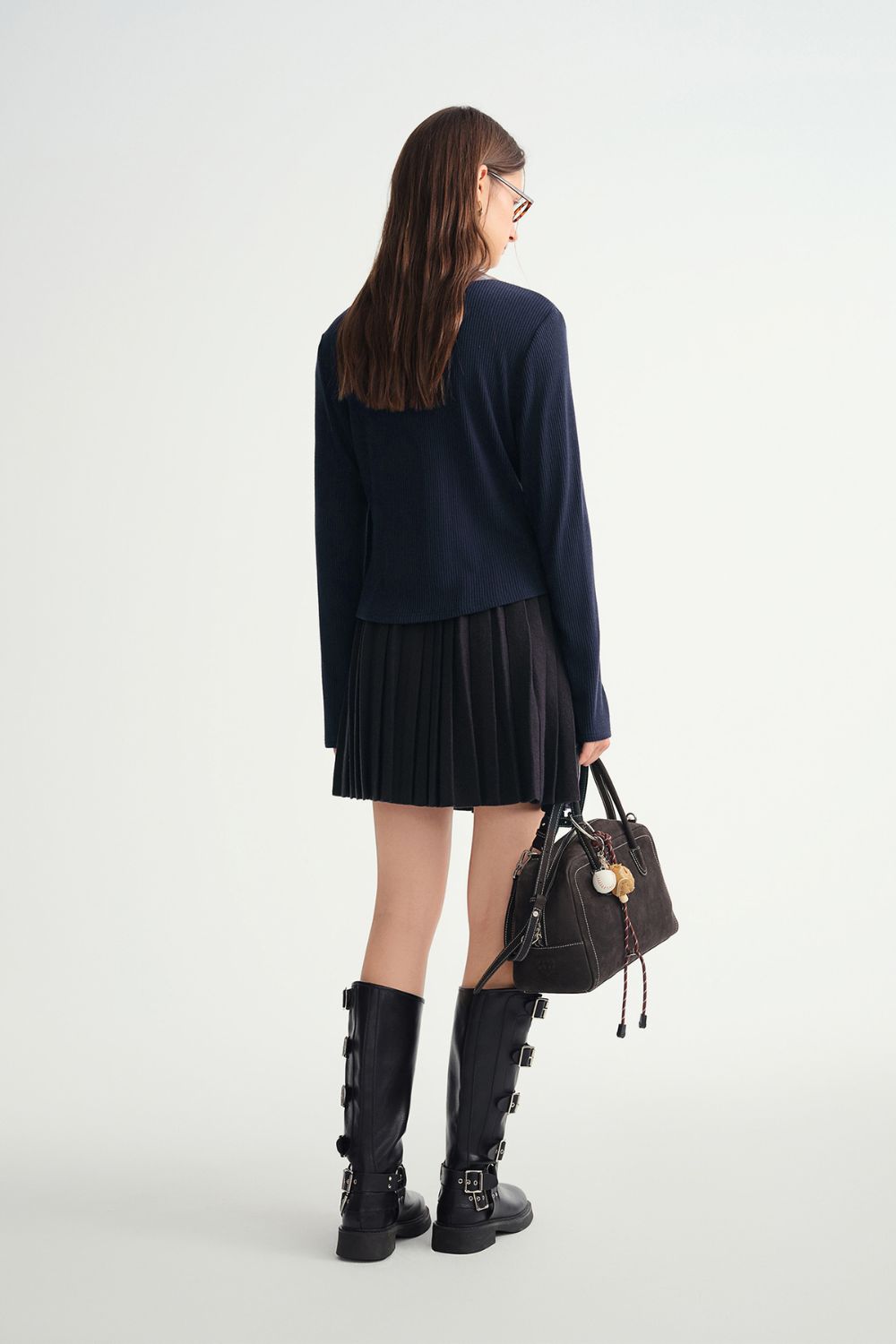 Rear view of navy blue pleated mini skirt and long-sleeve top