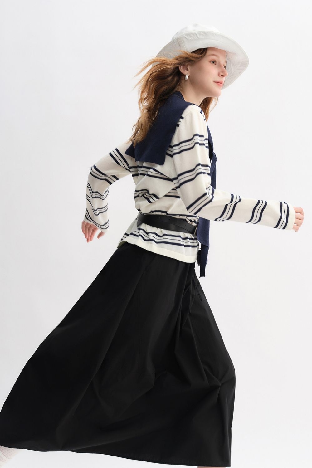 Side pose of model twirling in black skirt and striped sailor-style top