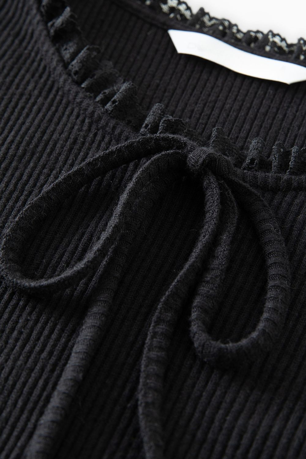 Close-up of neckline with bow detail on black ribbed dress