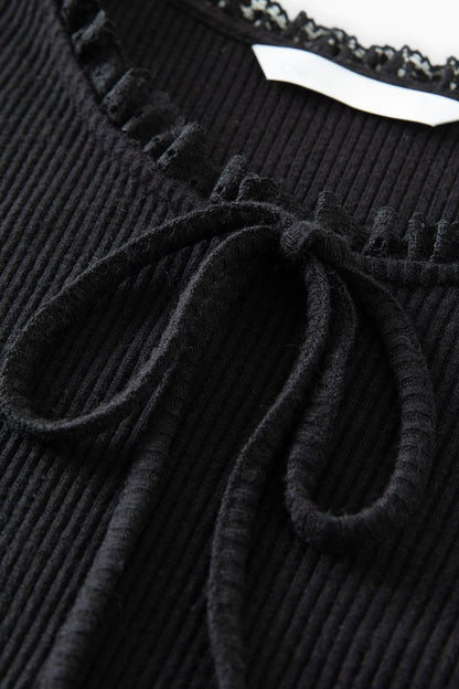 Close-up of neckline with bow detail on black ribbed dress