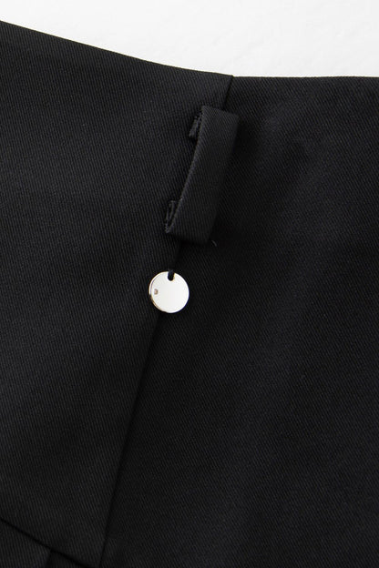 Close-up of button and waistband detail on pleated skirt