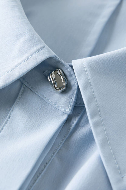 Close-up of button detail on light blue dress fabric