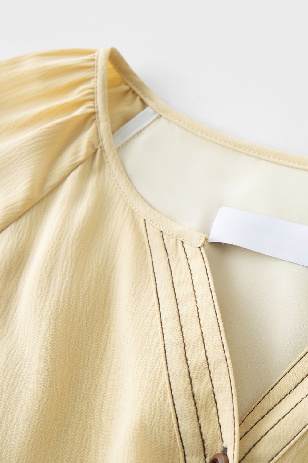 Close-up of neckline detail on yellow dress with subtle pleats