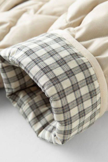 Close-up of beige jacket cuff with plaid lining