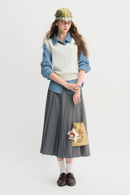 Model wearing gray pleated midi skirt with denim jacket and casual sneakers