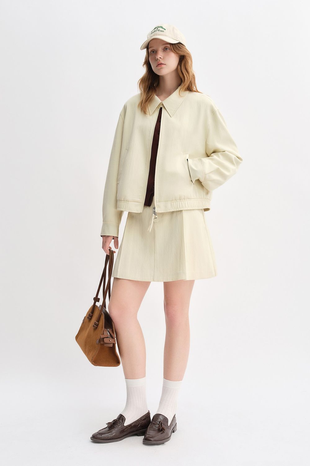 Model in cream jacket and skirt set with crossbody bag