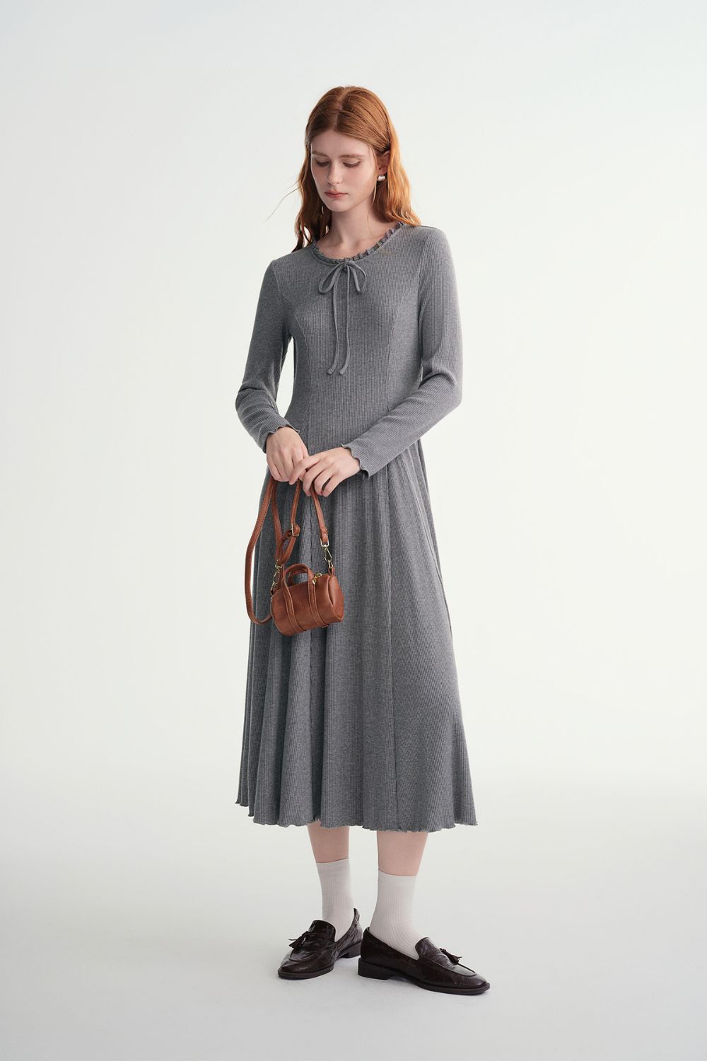 Model wearing gray ribbed midi dress with pleated skirt detail