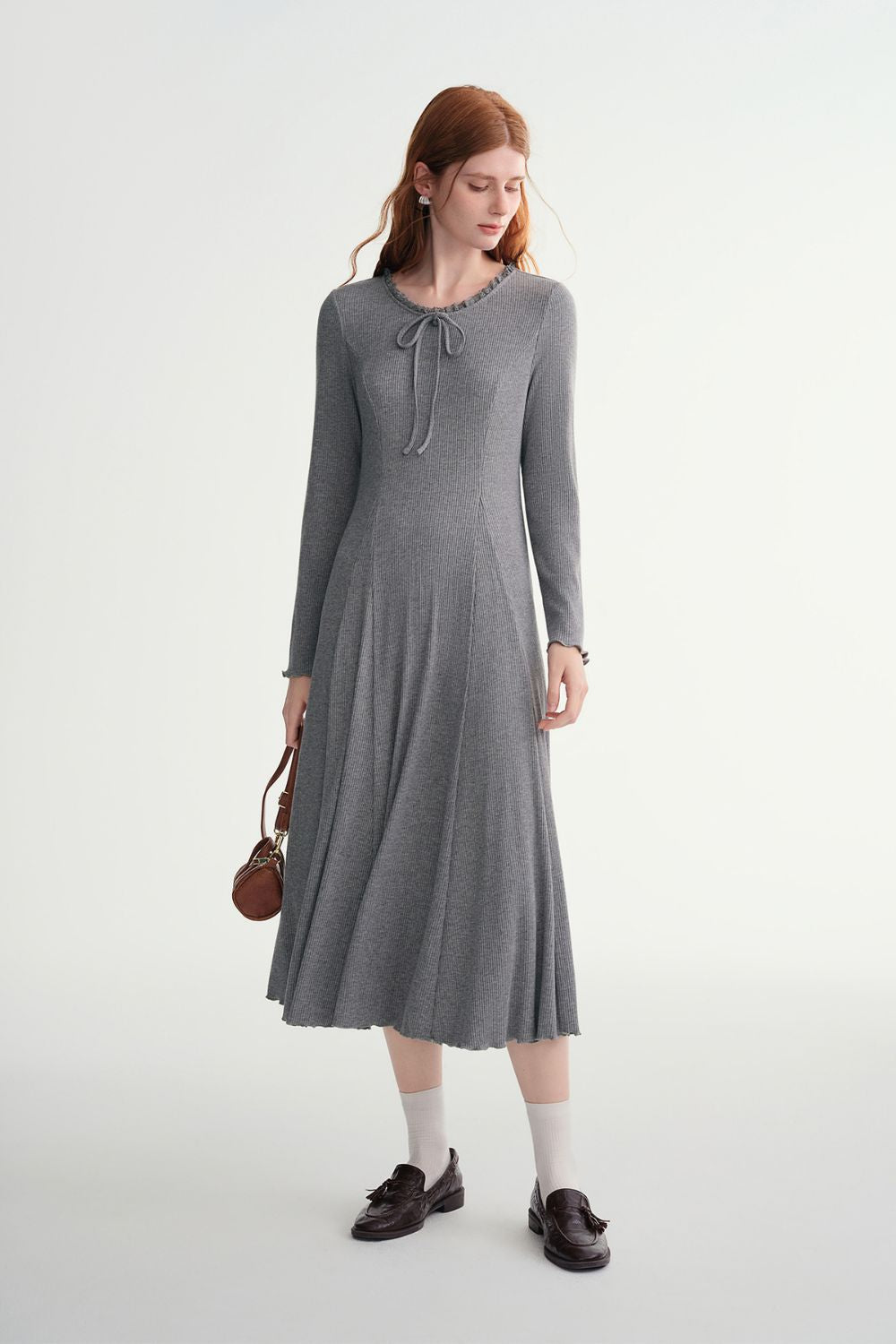 Side view of model in gray ribbed midi dress with pleated hem