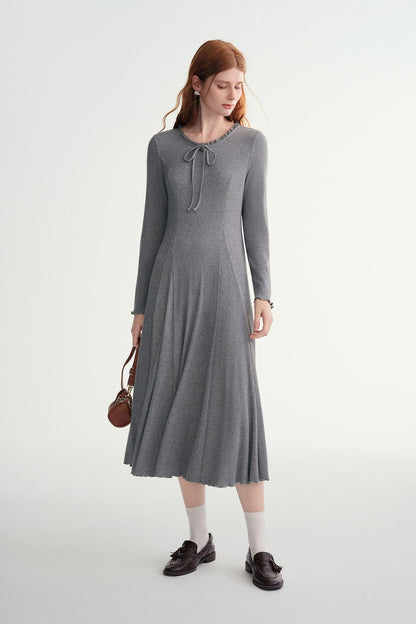 Side view of model in gray ribbed midi dress with pleated hem